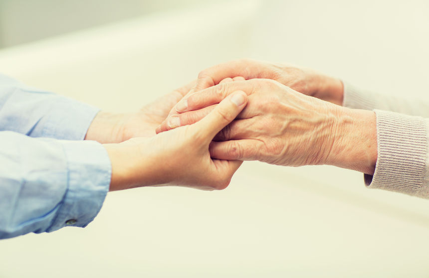 people, age, family, care and support concept - close up of senior and young woman  holding hands