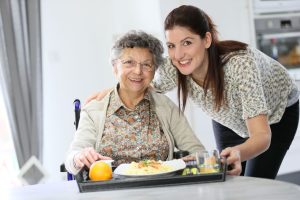 Homecarer preparing lunch for elderly woman